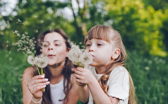 Mom and daughter blowing on dandelions