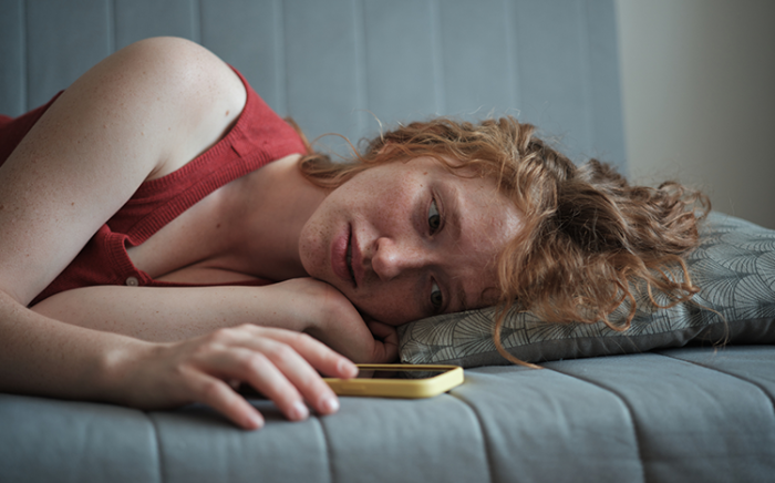 Girl laying on couch and looking at her phone and feeling concerned